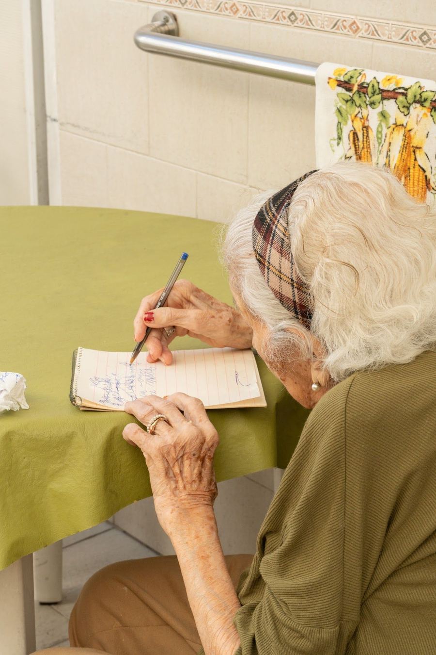 Una residente escribe en un cuaderno junto a la mesa